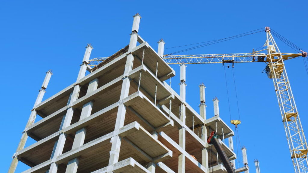 Estrutura de edifício em construção com grua ao fundo, representando o cumprimento de prazo na execução da obra